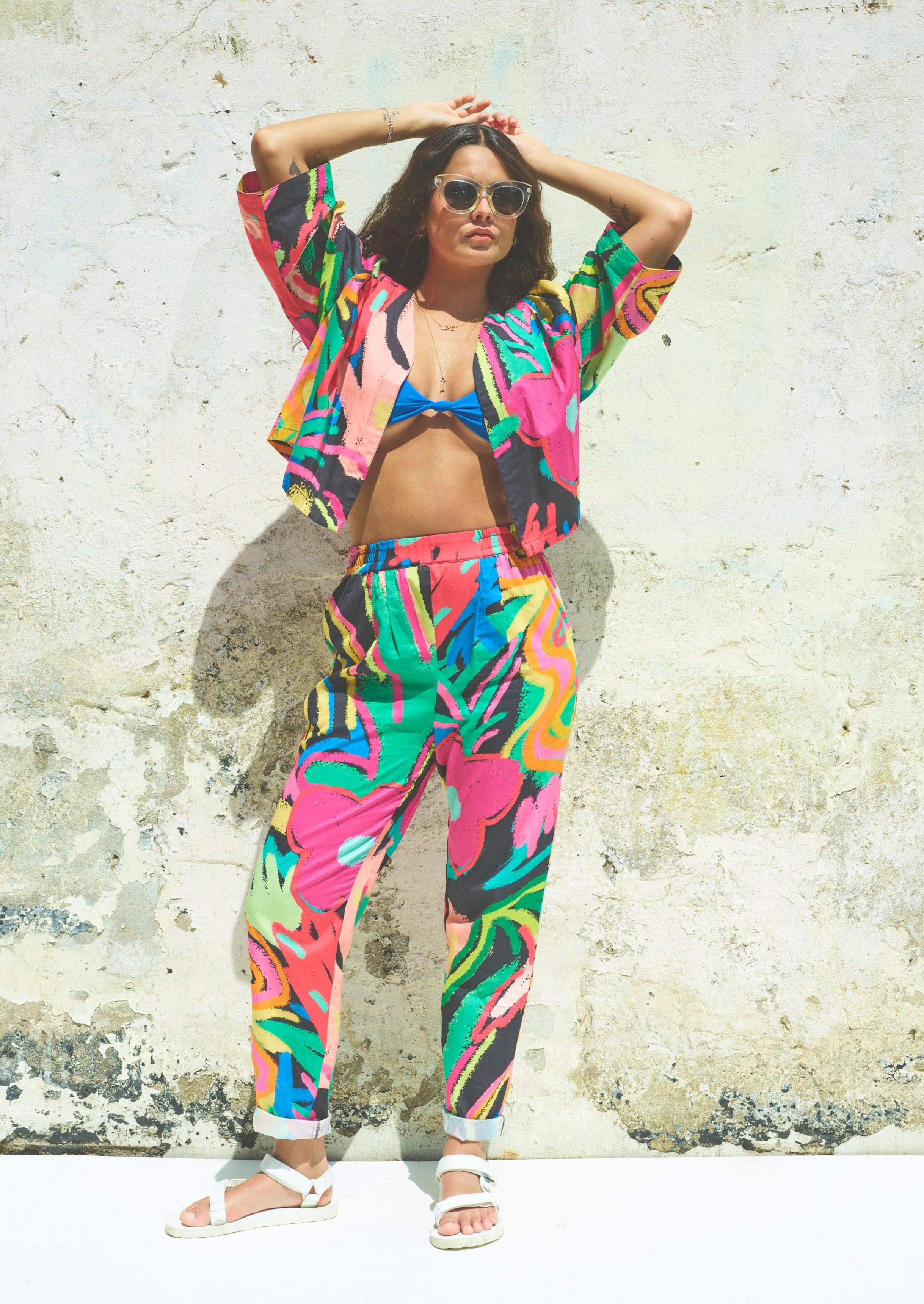 A pair of Miss Pompom Jungle Holiday Trousers with a vibrant hand-drawn tropical print in bright colors.