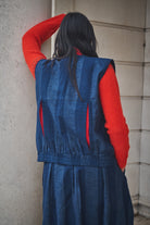 Person wearing Lowie denim stripe gilet against a stone wall.