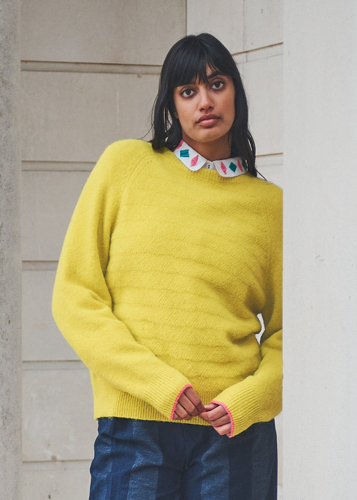 Woman wearing a bright yellow sweater with a neutral background