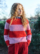 A striped Scottish jumper in pink and red with a round neckline and ribbed-knit hemline and trim around neck and wrist.