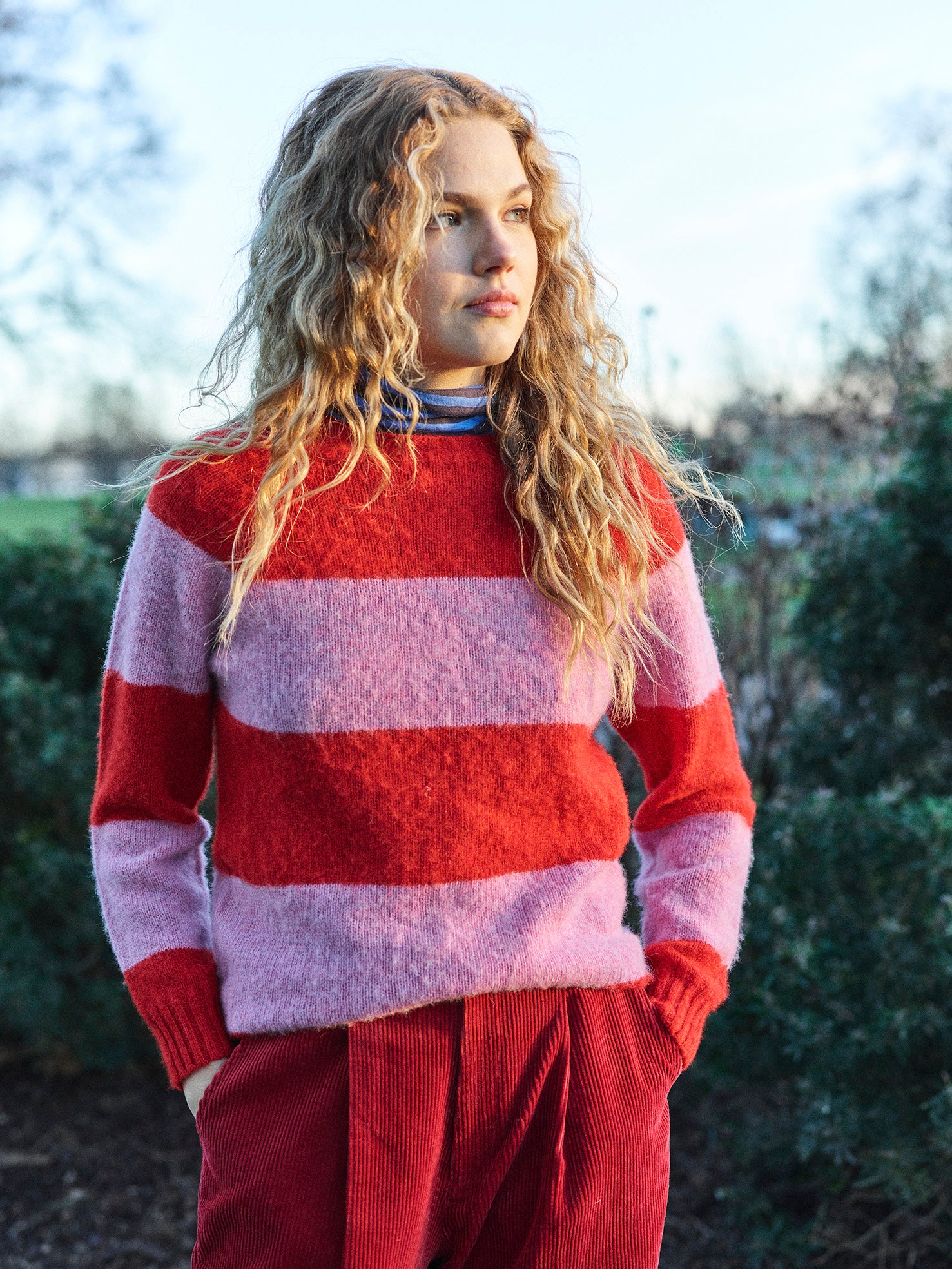 A striped Scottish jumper in pink and red with a round neckline and ribbed-knit hemline and trim around neck and wrist.