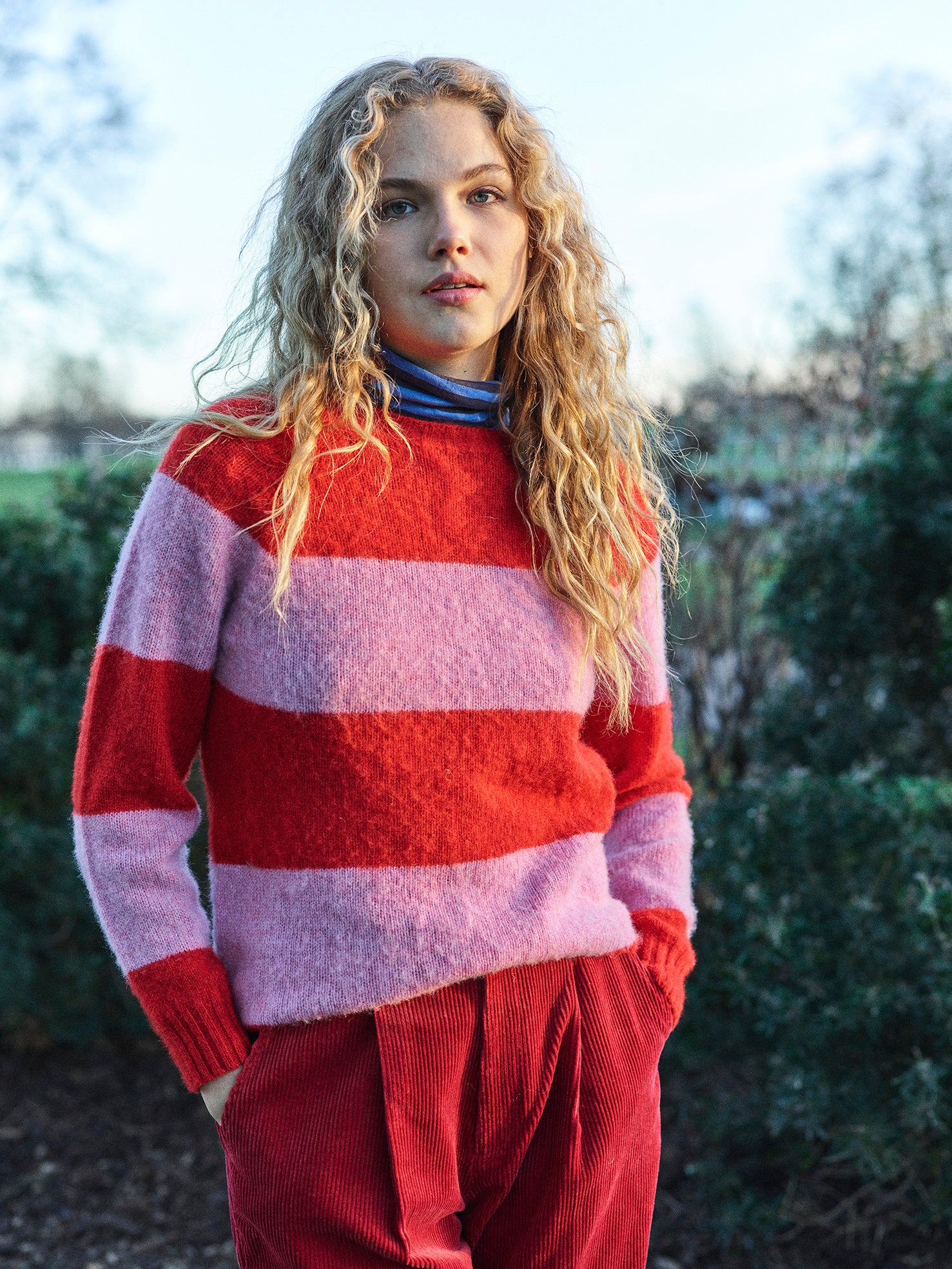 A striped Scottish jumper in pink and red with a round neckline and ribbed-knit hemline and trim around neck and wrist.