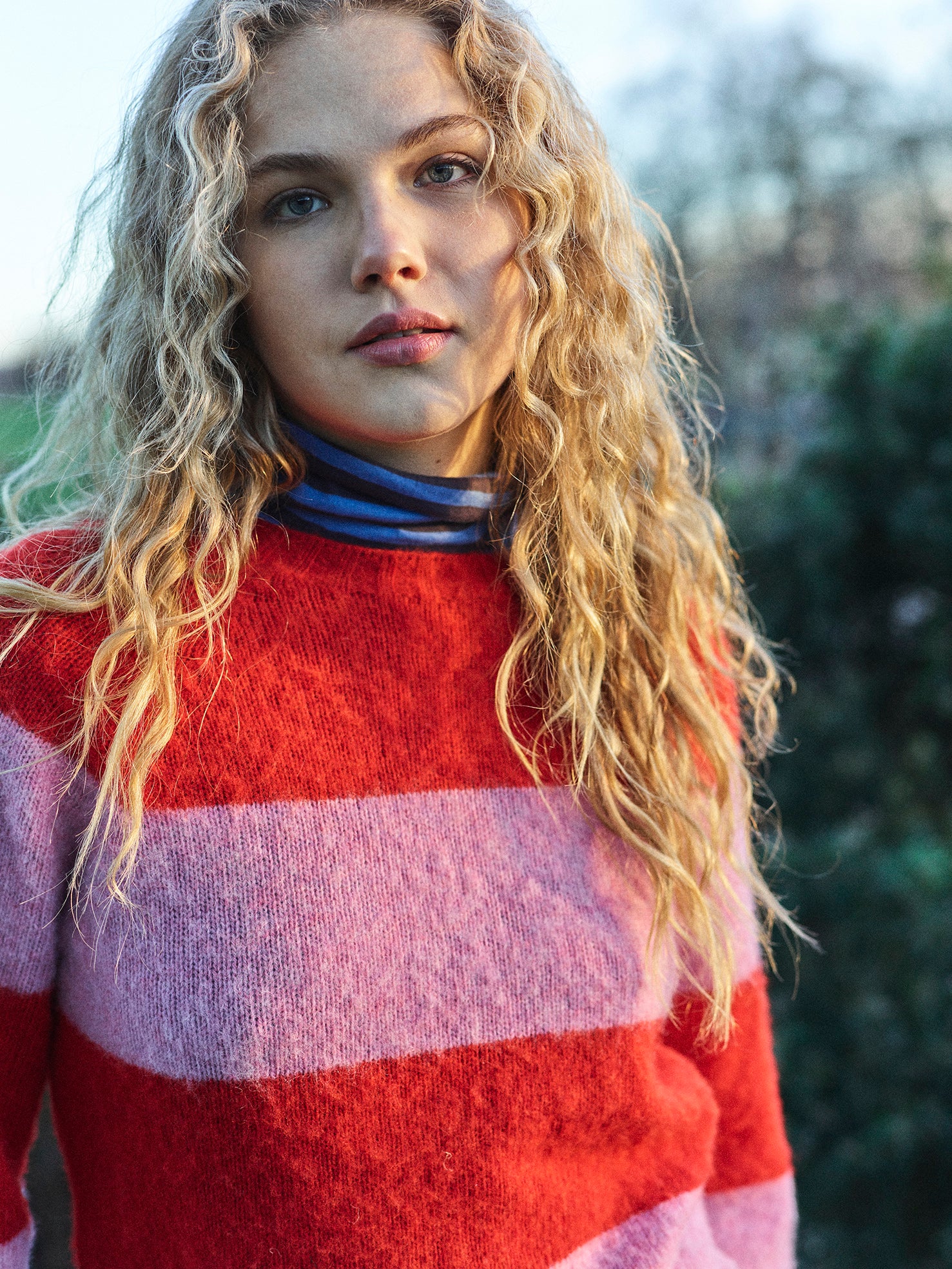 A striped Scottish jumper in pink and red with a round neckline and ribbed-knit hemline and trim around neck and wrist.