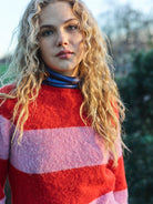 A striped Scottish jumper in pink and red with a round neckline and ribbed-knit hemline and trim around neck and wrist.