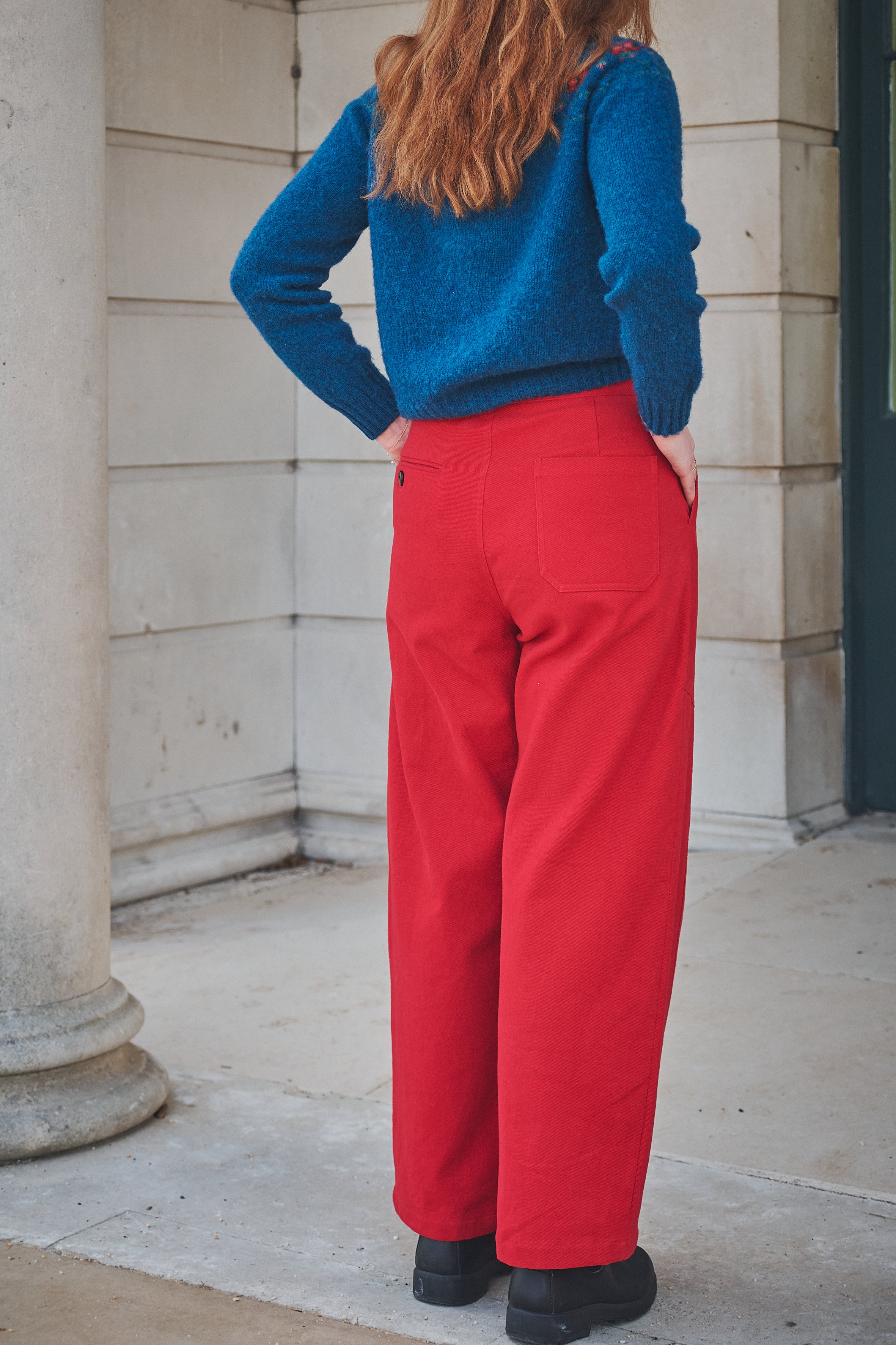 Person wearing a blue sweater and red pants standing outdoors.
