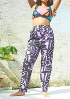 Full-length purple and black scribble print trousers with a high-rise fit and elasticated waistband, including pockets.