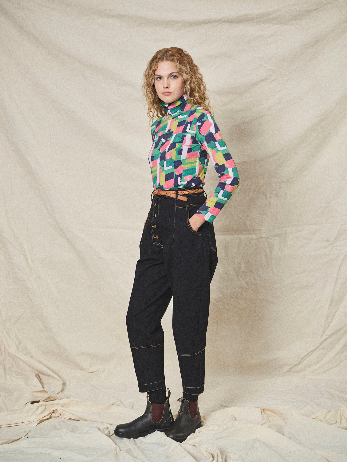 A pair of black cotton drill trousers with a high waist, wide beltband, and 5 button fly front. Features include slanted side pockets and raw stitching.