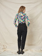 A pair of black cotton drill trousers with a high waist, wide beltband, and 5 button fly front. Features include slanted side pockets and raw stitching.