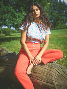A pair of red cotton linen trousers with side welt pockets and a row of buttons down the front.