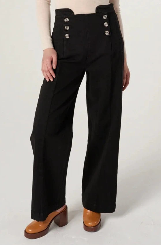 Woman wearing a sheer top and black pants on a white background