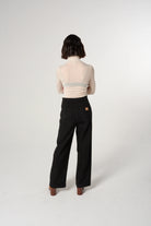 Person wearing a light pink top and black pants on a white background