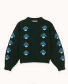 A dark forest green crewneck sweater featuring an all-over pattern of blue and white embroidered mushrooms, laid flat against a light cream background.