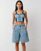 Woman wearing a denim crop top and shorts on a white background