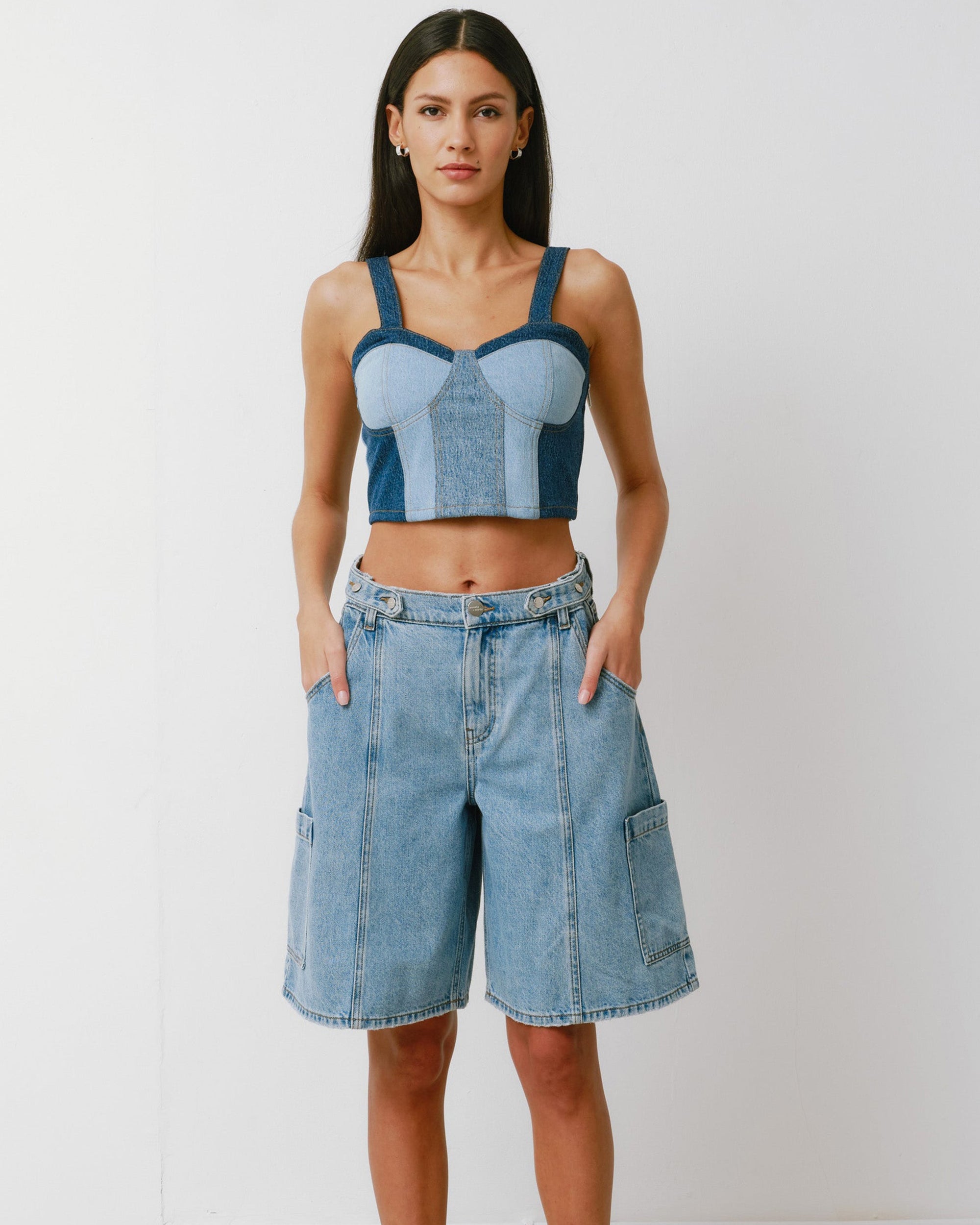 Woman wearing a denim crop top and shorts on a white background