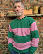 A man wearing a pink and green striped jumper with a round neckline.