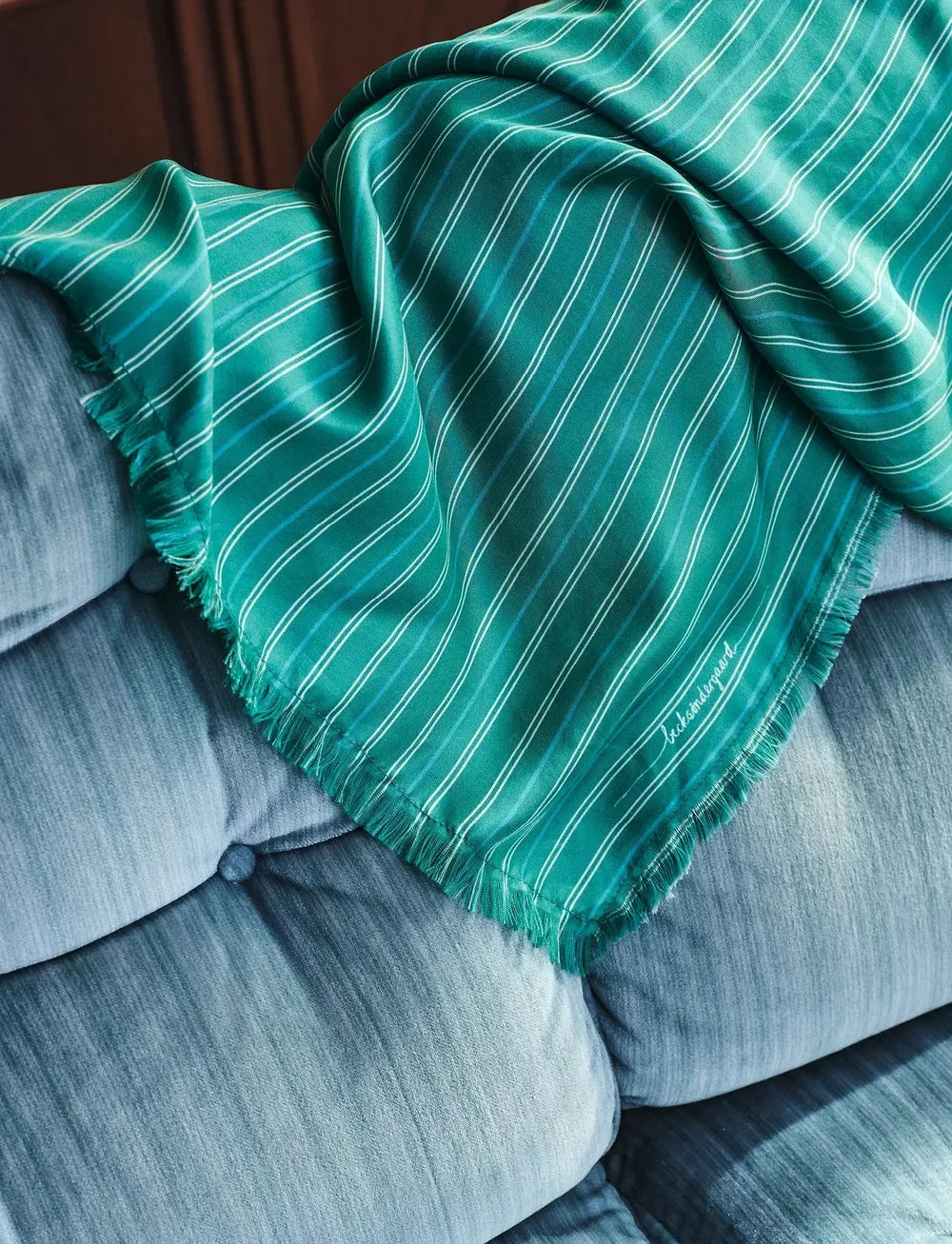 Green striped blanket draped over a gray sofa
