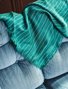 Green striped blanket draped over a gray sofa