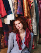 Woman with red hair sitting in front of a rack of colorful clothing