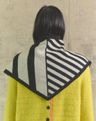 Person wearing a yellow coat with a patterned hood against a beige wall