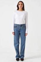 Person wearing a white long-sleeve shirt and blue jeans on a white background