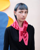 Person wearing a pink scarf with a colorful abstract background