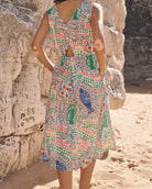 Person wearing a colorful patterned dress standing against a stone wall.