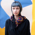 Person wearing a colorful checkered scarf against a geometric background
