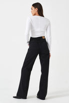 Person wearing a white long-sleeve top and black pants on a white background