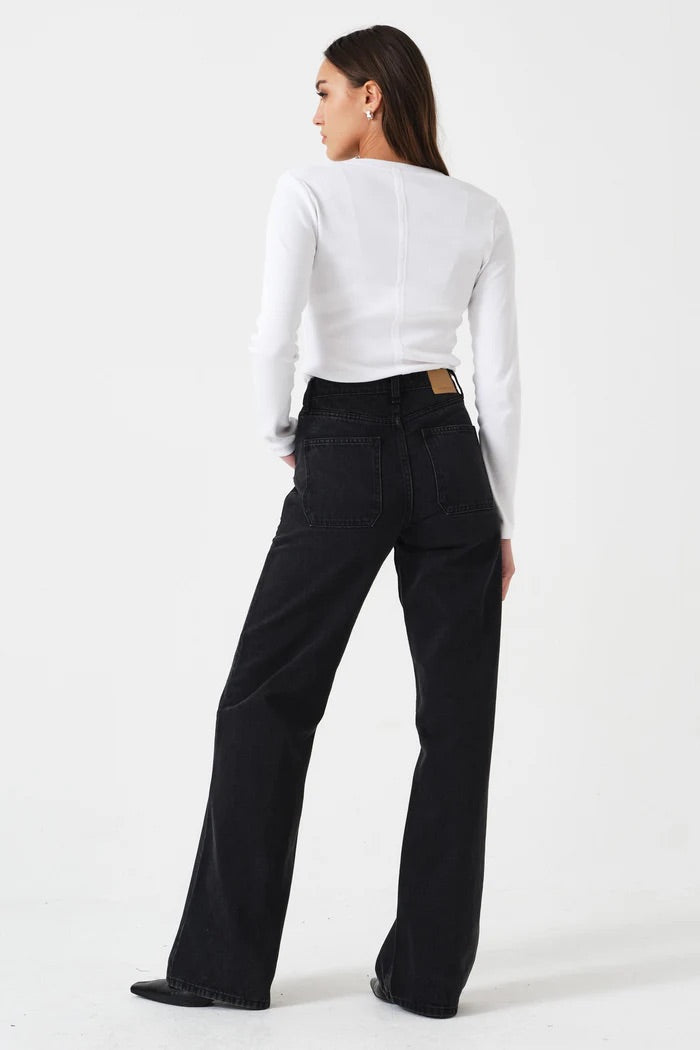 Person wearing a white long-sleeve top and black pants on a white background