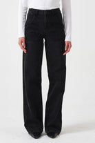 Person wearing black flared jeans and a white long-sleeve shirt on a white background