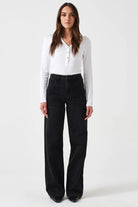 Woman wearing a white long-sleeve shirt and black pants on a white background