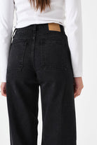 Person wearing black jeans with a white shirt on a plain background