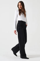 Woman wearing a white blouse and black pants on a white background