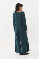 Woman wearing a teal long-sleeve jumpsuit on a white background