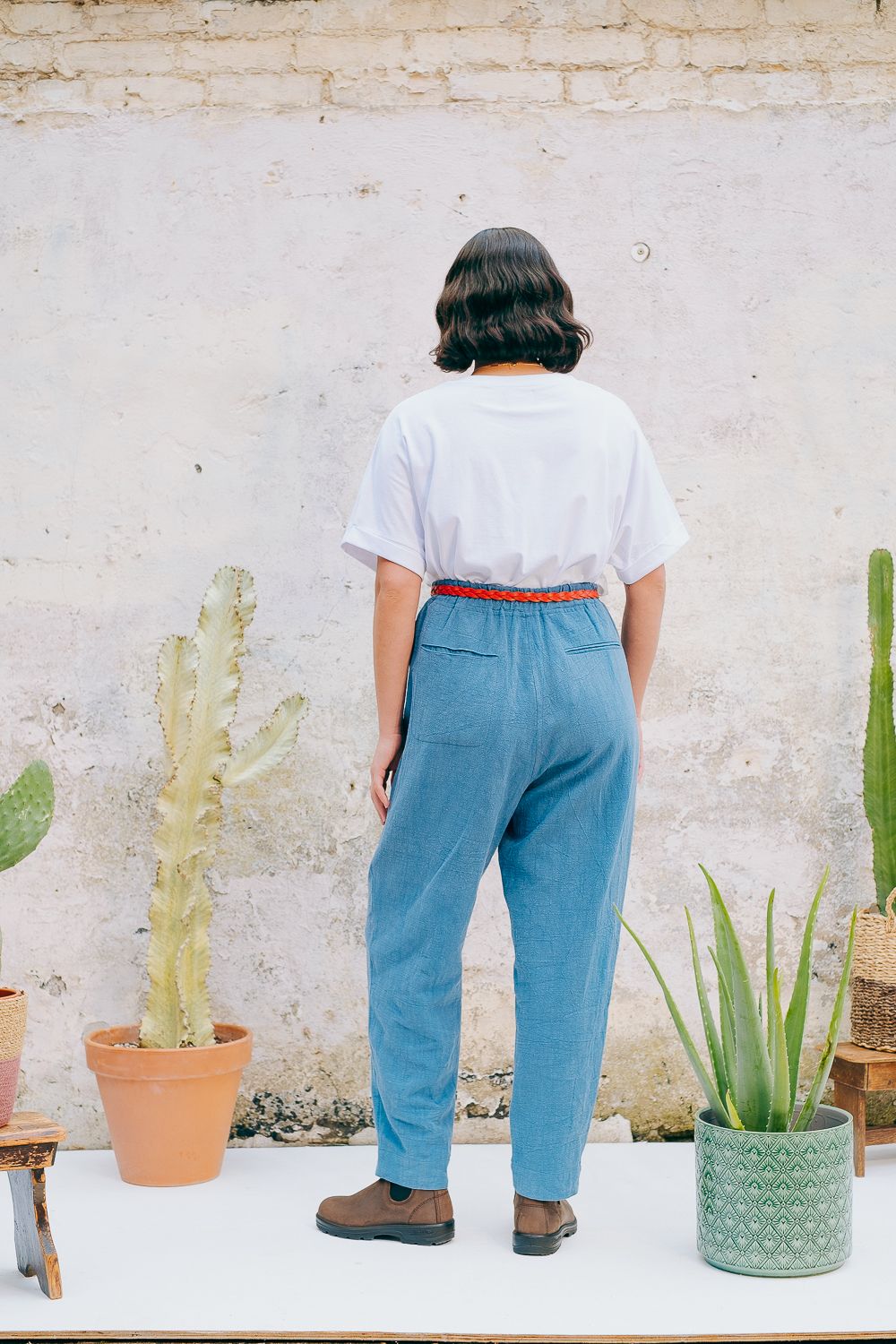 Washed blue cotton linen trousers with side welt pockets and elasticated waist at the back, featuring five corozo buttons down the front.
