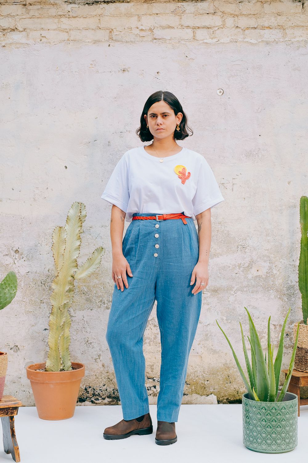 Washed blue cotton linen trousers with side welt pockets and elasticated waist at the back, featuring five corozo buttons down the front.