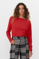 Woman wearing a red top and checkered pants on a white background