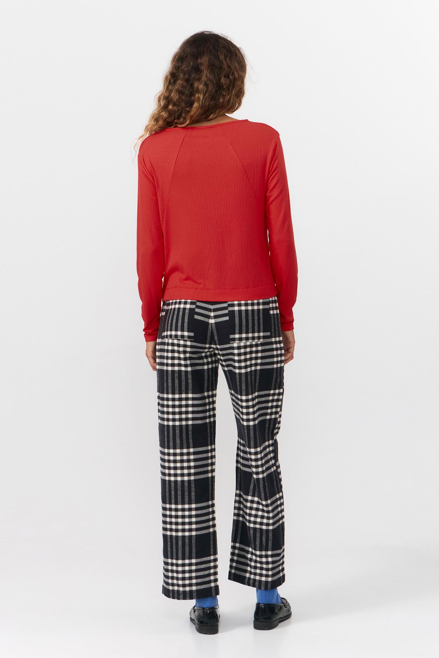 Person wearing a red top and checkered pants on a white background