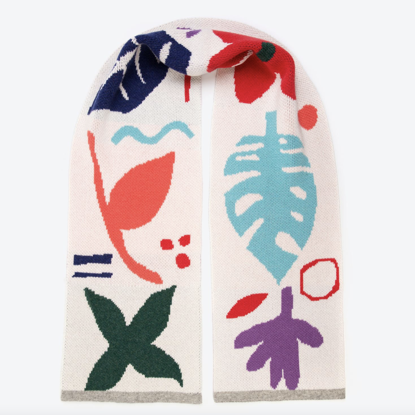 A cream wool scarf with a botanical pattern featuring mismatched shapes in various colors including green, red, blue, purple, pink, and turquoise, finished with a light grey edging.